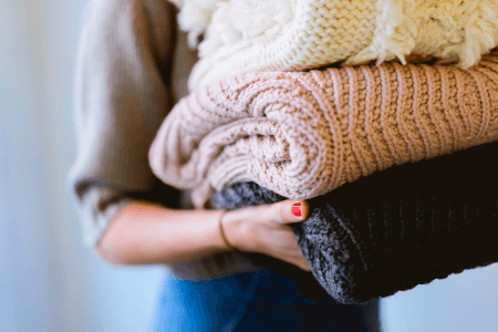 Woman holding sweaters